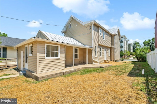 rear view of house featuring a lawn and a patio