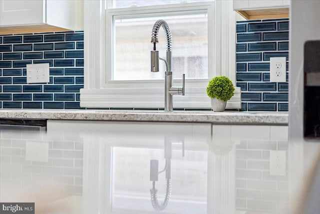 details featuring decorative backsplash, light stone countertops, and white cabinets