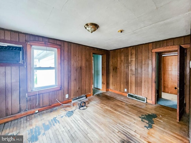 empty room with wooden walls, a wall unit AC, and wood-type flooring