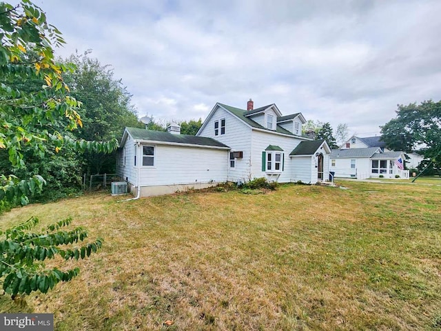 rear view of property featuring central AC and a lawn