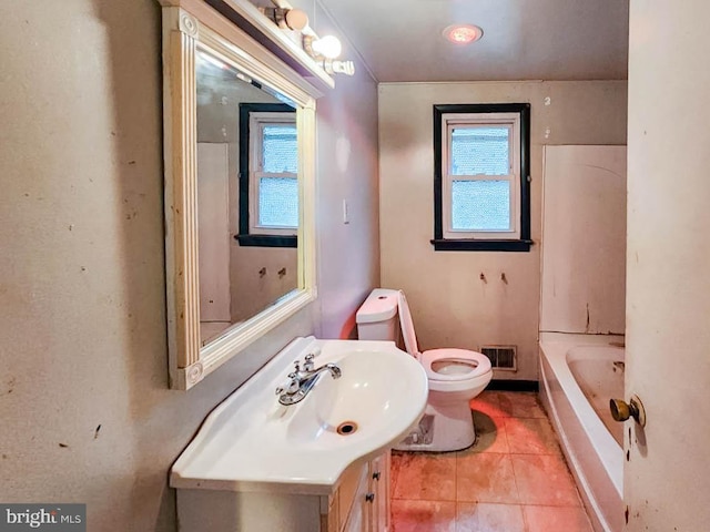 bathroom with tile patterned floors, toilet, a bath, and vanity