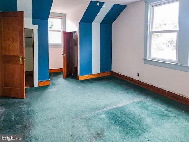 bonus room featuring lofted ceiling and dark carpet