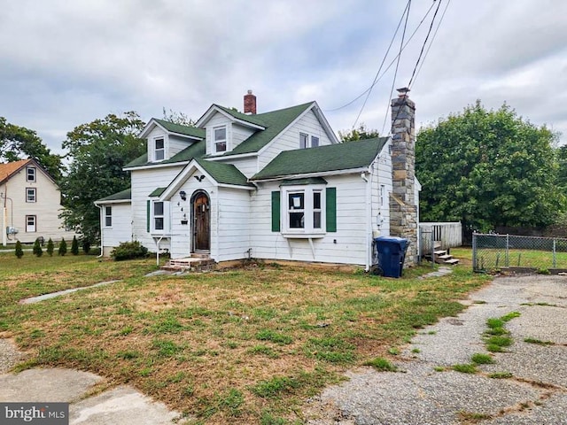 cape cod home featuring a front lawn