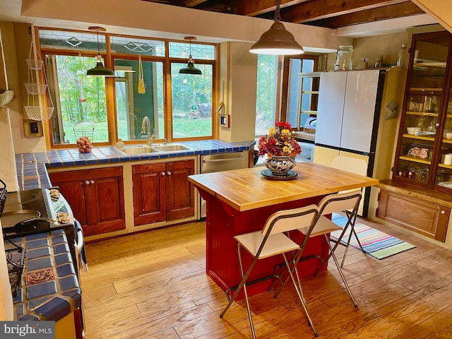 kitchen featuring tile countertops, beam ceiling, sink, and light wood-type flooring