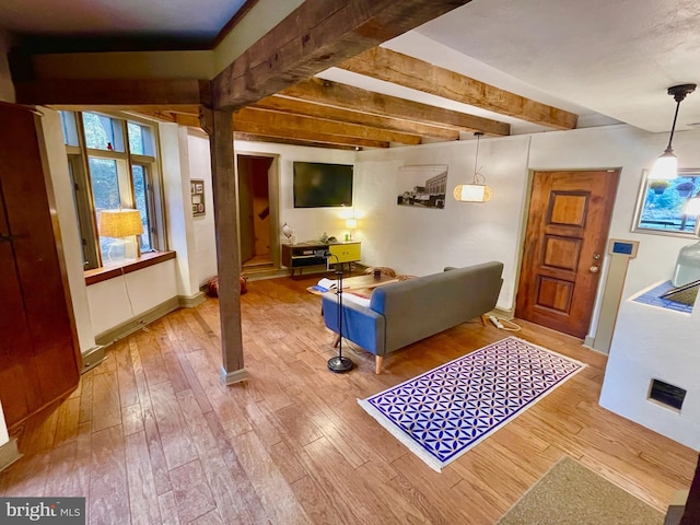 living room featuring beamed ceiling and light hardwood / wood-style floors