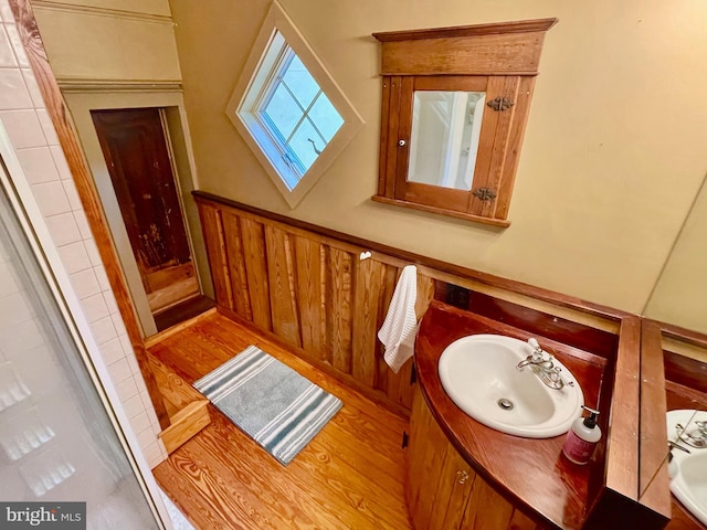 bathroom with a shower, vanity, wood walls, and hardwood / wood-style flooring