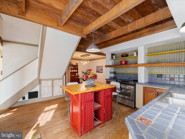 kitchen with butcher block counters, a kitchen bar, a center island, light wood-type flooring, and stainless steel range