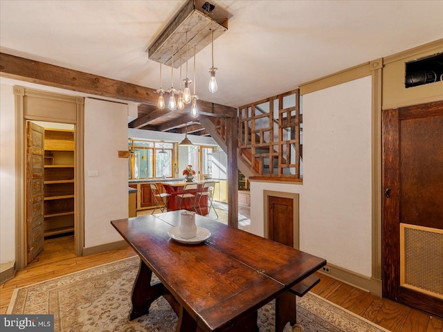 dining room featuring beamed ceiling and light hardwood / wood-style flooring