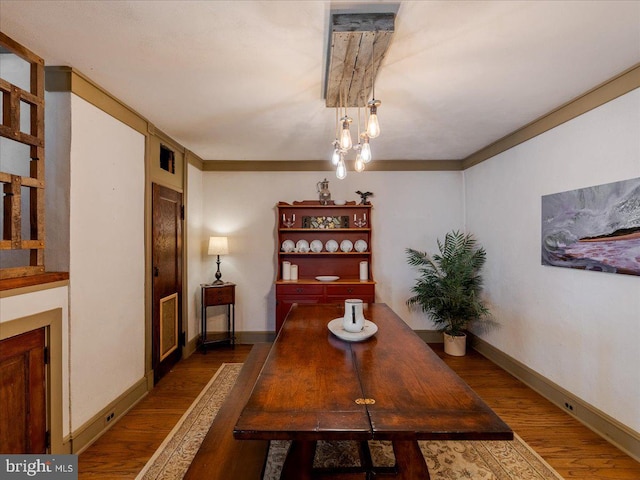 dining space with ornamental molding and dark wood-type flooring