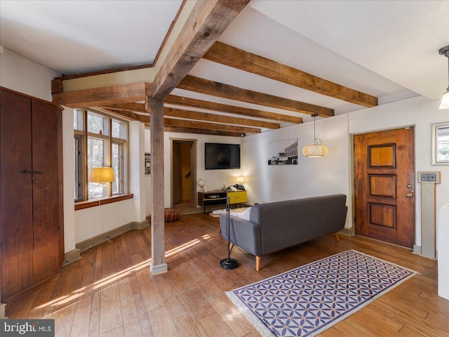 living room featuring beamed ceiling, hardwood / wood-style floors, and plenty of natural light