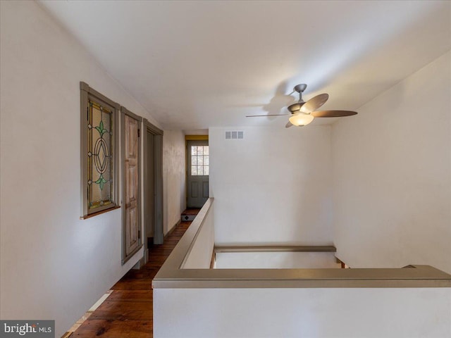 stairs with hardwood / wood-style floors and ceiling fan