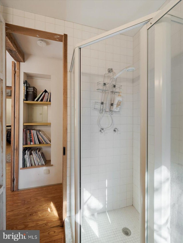 bathroom with built in shelves, an enclosed shower, and hardwood / wood-style flooring