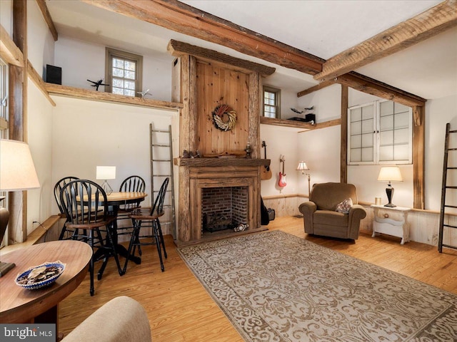 sitting room featuring a towering ceiling, beamed ceiling, and light wood-type flooring