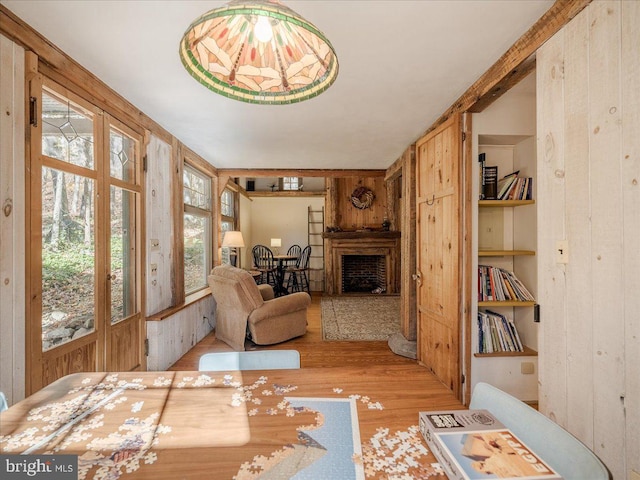 living room with built in features, wooden walls, and light hardwood / wood-style floors