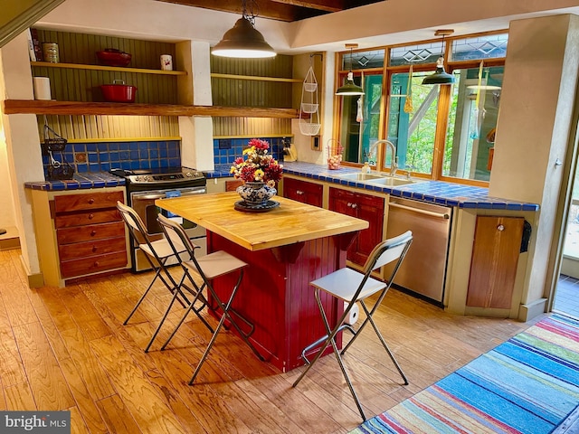 kitchen with sink, appliances with stainless steel finishes, tile counters, and tasteful backsplash