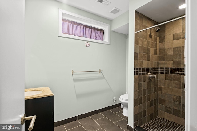 bathroom with tile patterned floors, vanity, tiled shower, and toilet