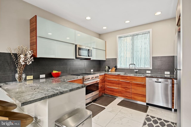 kitchen featuring sink, kitchen peninsula, backsplash, appliances with stainless steel finishes, and dark stone countertops