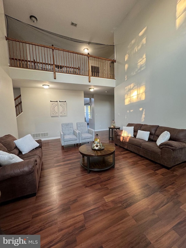 living room featuring a towering ceiling and dark hardwood / wood-style flooring