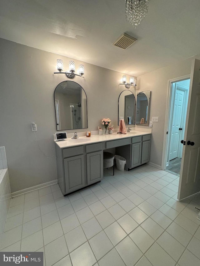 bathroom featuring tile patterned floors, an inviting chandelier, vanity, and a bathing tub