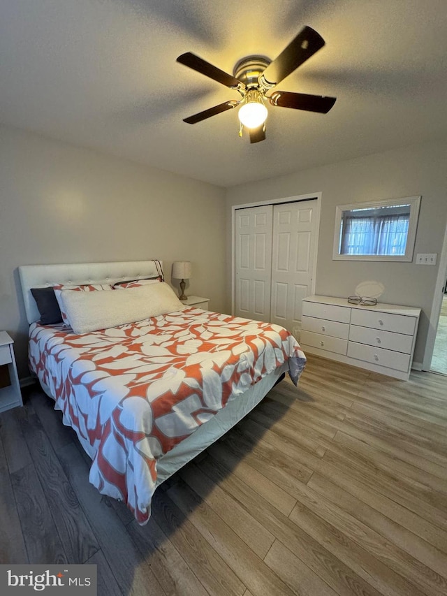 bedroom with ceiling fan, a closet, wood-type flooring, and a textured ceiling