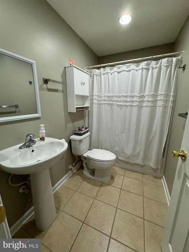 full bathroom with shower / tub combo with curtain, tile patterned floors, sink, and toilet