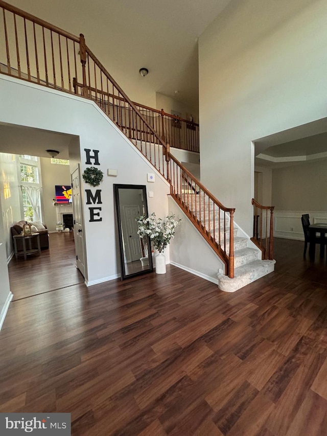 stairway with a towering ceiling and hardwood / wood-style flooring