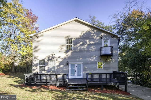 back of house with french doors, a lawn, a wooden deck, and a balcony