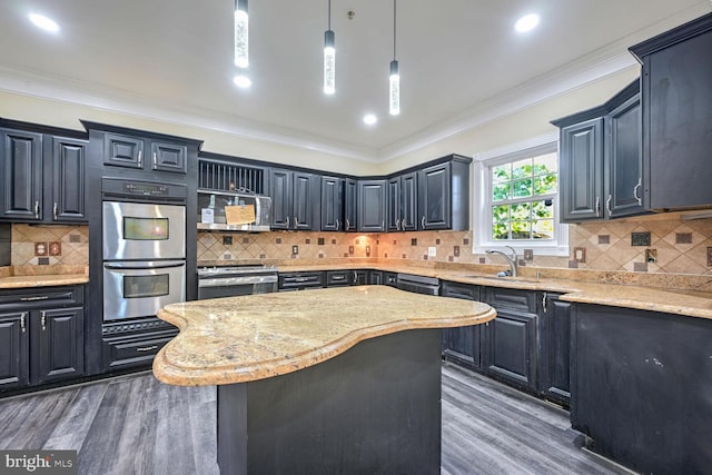 kitchen with hanging light fixtures, appliances with stainless steel finishes, dark wood-type flooring, sink, and a center island