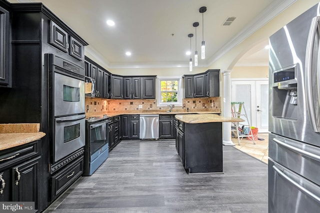 kitchen with dark hardwood / wood-style flooring, a kitchen island, decorative columns, stainless steel appliances, and decorative light fixtures