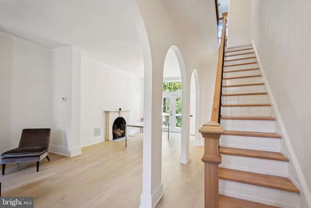 staircase featuring ornamental molding, french doors, and wood-type flooring