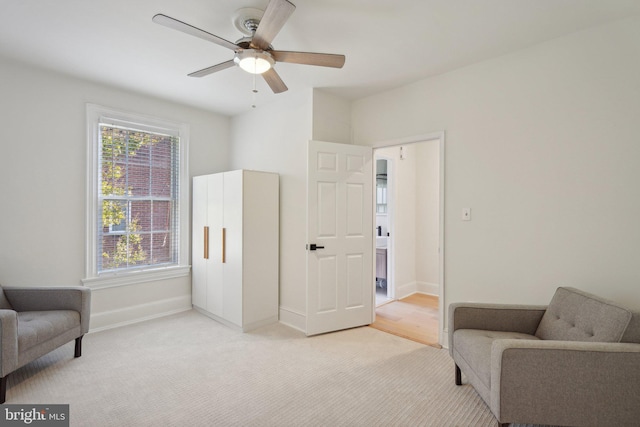 sitting room with ceiling fan and light colored carpet