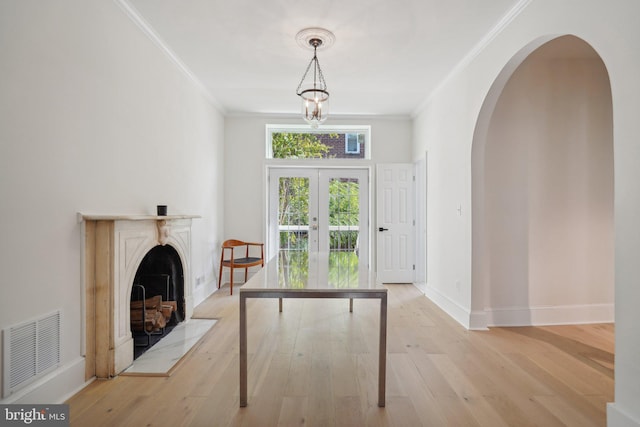 interior space featuring french doors, an inviting chandelier, ornamental molding, and light hardwood / wood-style flooring