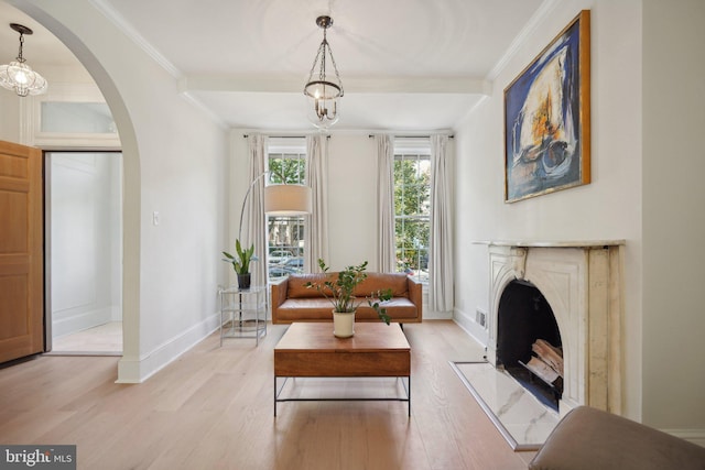 sitting room with a high end fireplace, ornamental molding, and light wood-type flooring