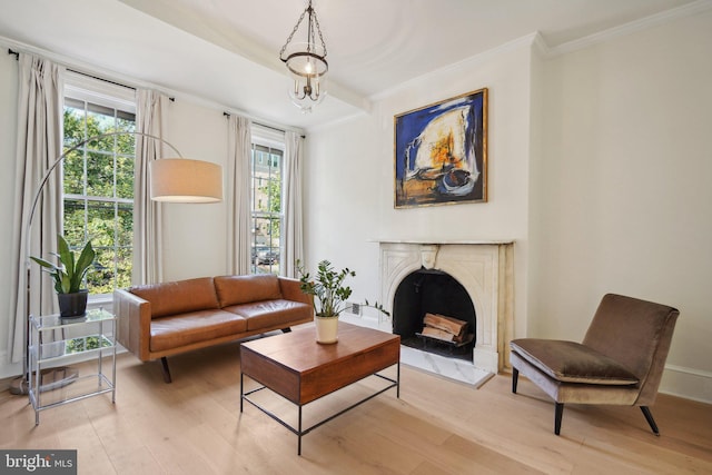 sitting room featuring a notable chandelier, light hardwood / wood-style flooring, ornamental molding, and a high end fireplace