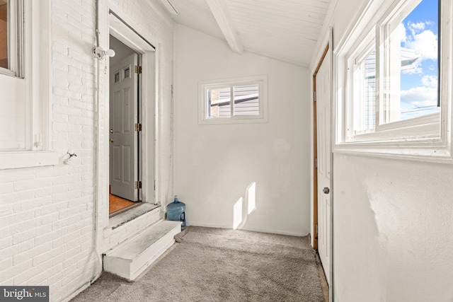 corridor featuring carpet floors, vaulted ceiling with beams, and plenty of natural light