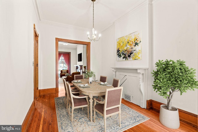 dining area with hardwood / wood-style floors, a chandelier, and crown molding