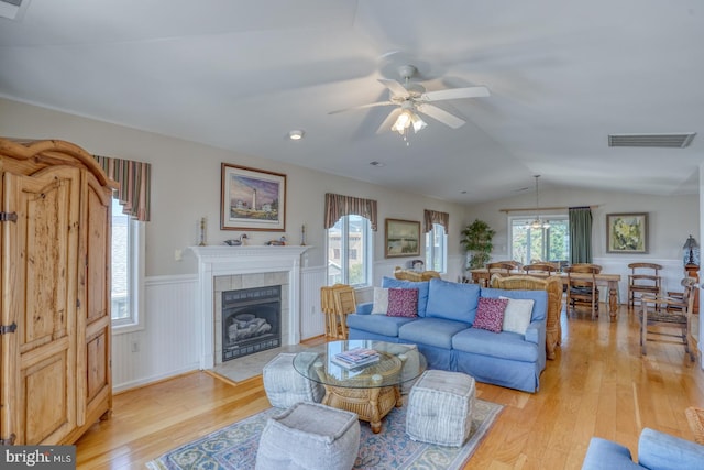 living room featuring lofted ceiling, ceiling fan, light hardwood / wood-style floors, and a tiled fireplace