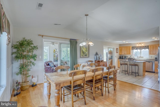 dining space featuring ceiling fan with notable chandelier, lofted ceiling, and light hardwood / wood-style flooring