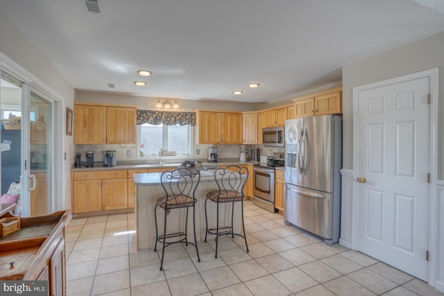 kitchen featuring stainless steel appliances, backsplash, light brown cabinets, and a kitchen island