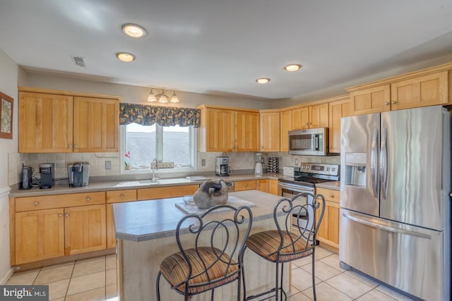 kitchen featuring stainless steel appliances, light tile patterned flooring, a kitchen island, and sink