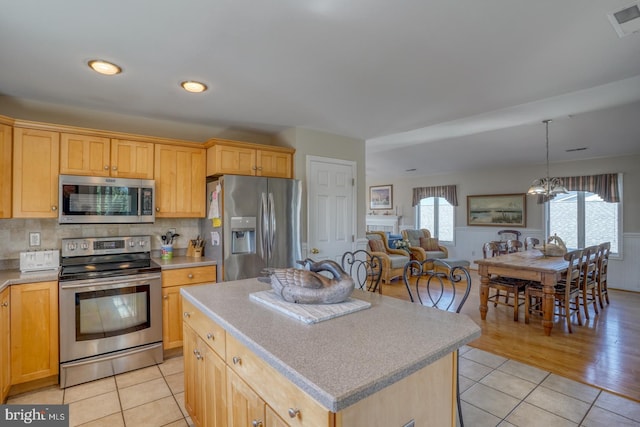 kitchen featuring light hardwood / wood-style floors, appliances with stainless steel finishes, a kitchen island, and a healthy amount of sunlight