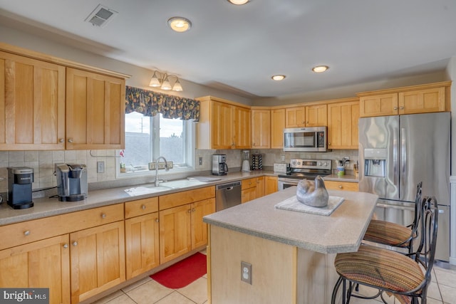 kitchen with light tile patterned flooring, a kitchen island, a kitchen breakfast bar, and stainless steel appliances