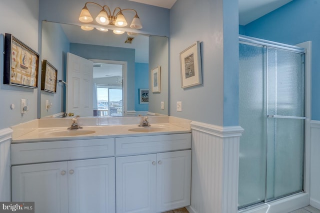 bathroom featuring a shower with shower door and vanity