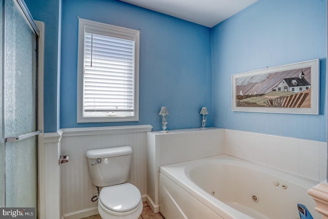 bathroom with a tub to relax in and toilet