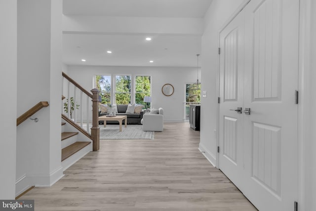 hallway with recessed lighting, stairs, baseboards, and light wood-style floors