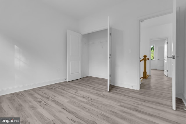 unfurnished bedroom featuring baseboards, light wood-type flooring, and a closet