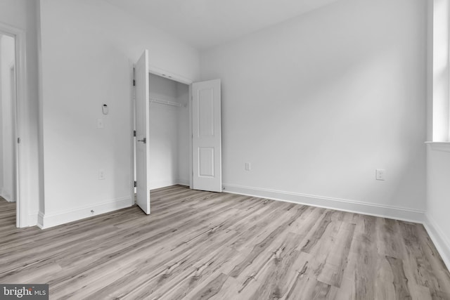 unfurnished bedroom with baseboards, wood finished floors, and a closet