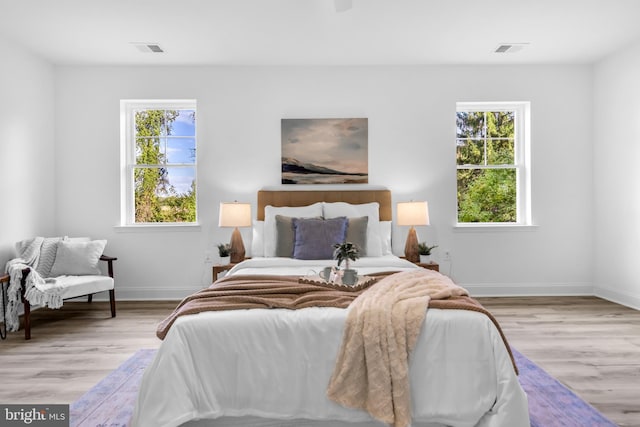 bedroom with visible vents, wood finished floors, and baseboards