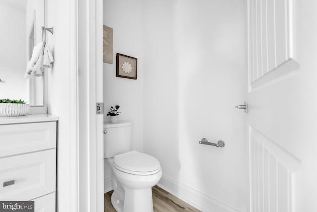 bathroom featuring wood finished floors, toilet, vanity, and baseboards
