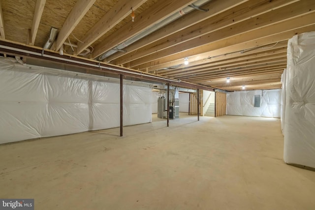 unfinished below grade area featuring stairs, heating unit, and electric panel